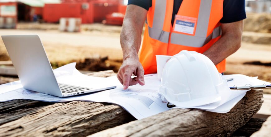 Closeup of contractor in construction site pointing at plan on wooden sleeper